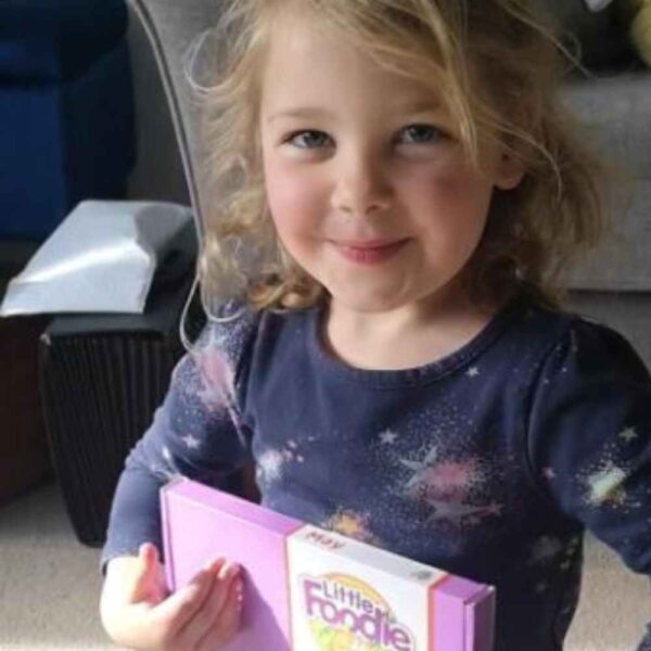 The Little Foodies Club food programme for kids, image of a child beaming a smile holding their latest purple box that came through the post.
